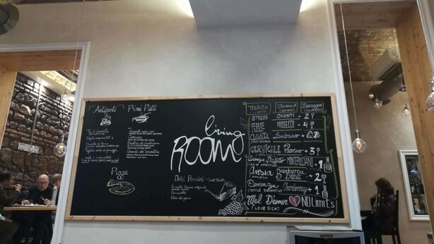 L’intérieur d’un restaurant, avec un tableau noir servant de menu, où sont indiqués différents plats et leurs prix.