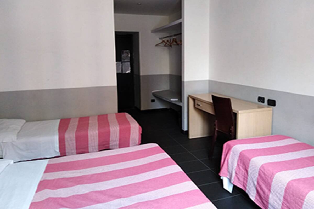 A hotel room with two beds, a desk, and a wardrobe.