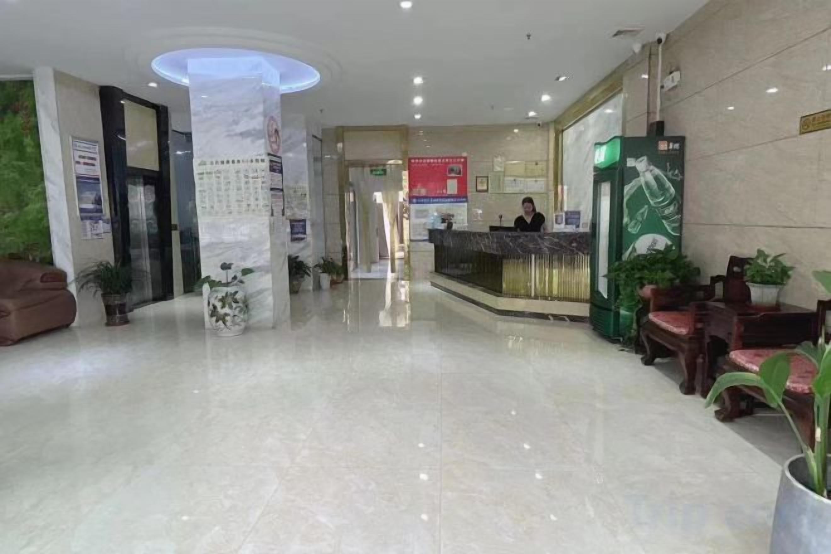A hotel lobby with a reception desk, seating area, and a large pillar.