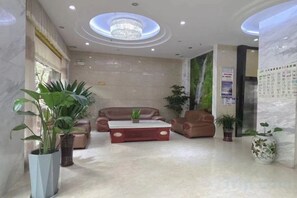 Un vestíbulo de hotel con candelabro, zona de estar y plantas en macetas.