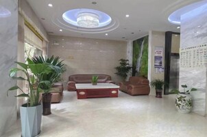 Un vestíbulo de hotel con candelabro, zona de estar y plantas en macetas.