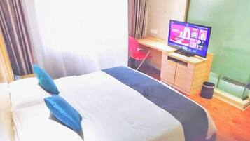 Habitación de hotel con cama, televisor sobre un soporte de madera y escritorio con silla.