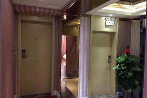 Un pasillo de hotel con una puerta cerrada, una planta y una lámpara en el techo.