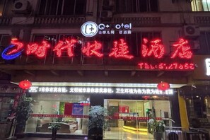 A hotel with a prominent red neon sign, a visible entrance, and a signboard with text.