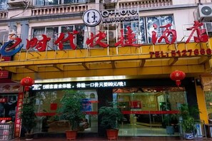 Entrada de hotel con un toldo amarillo, faroles rojos y un letrero con caracteres chinos.