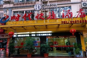 Entrada de hotel con un toldo amarillo, faroles rojos y un letrero con caracteres chinos.