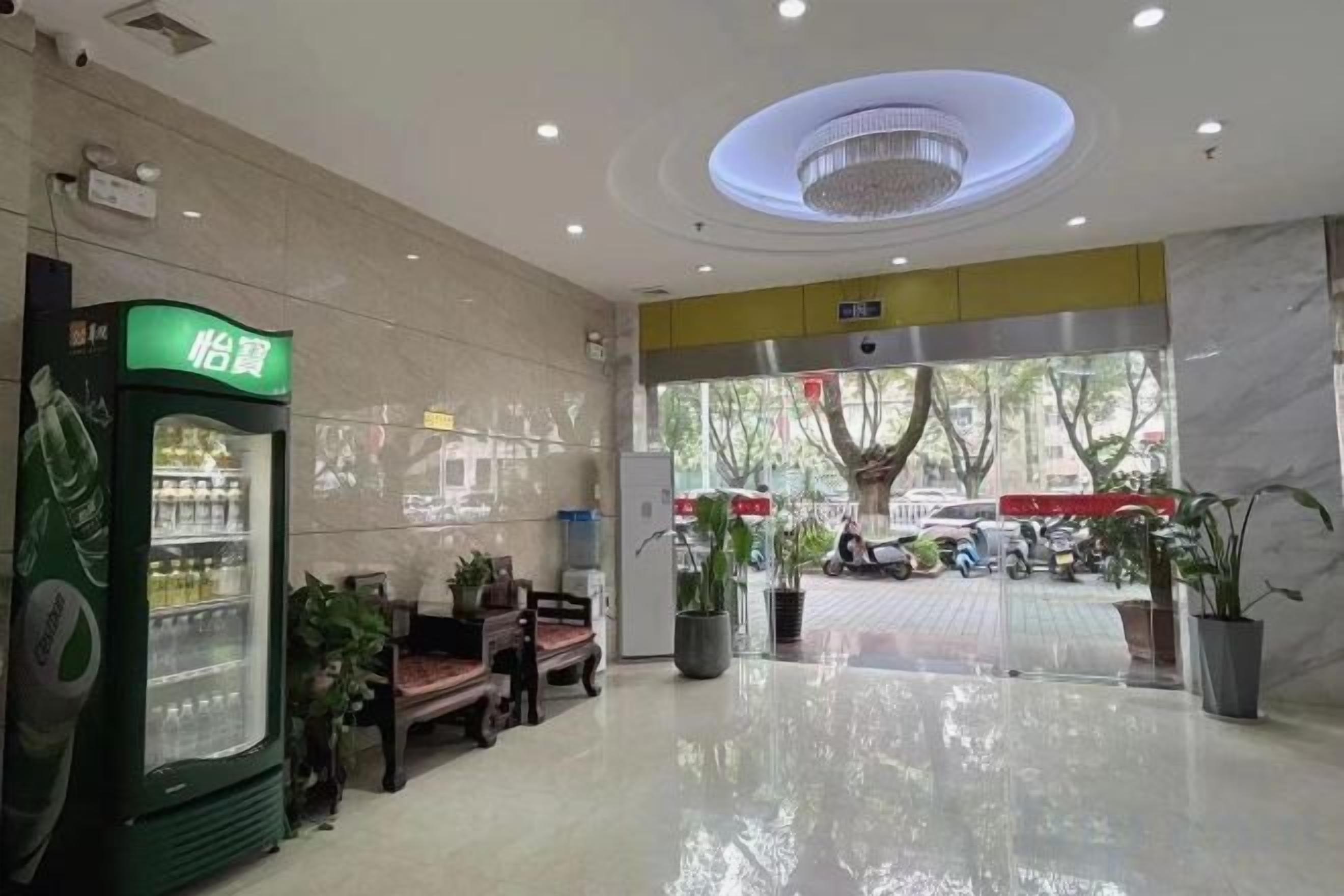 Un vestíbulo de hotel con mostrador de recepción, zona de estar y máquina expendedora.