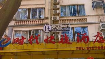 A hotel with a yellow facade and a sign indicating it is a hotel.