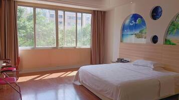 A hotel room with a large bed, a desk, and a chair. There is a window with curtains, and a painting on the wall.