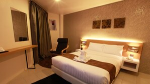 A hotel room with a bed, a chair, a desk, and a nightstand with a phone. - DWJ Hotel (Ipoh)