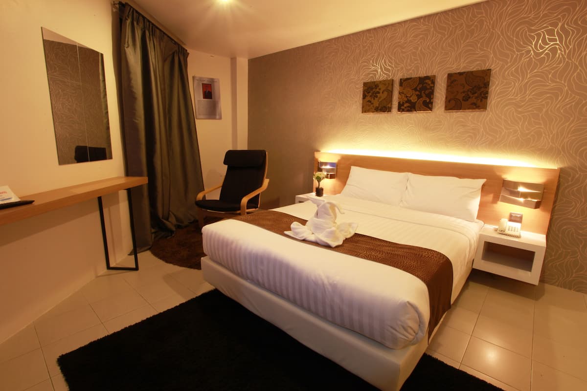Una habitación de hotel con una cama, una silla, un escritorio y una mesita de noche con un teléfono.