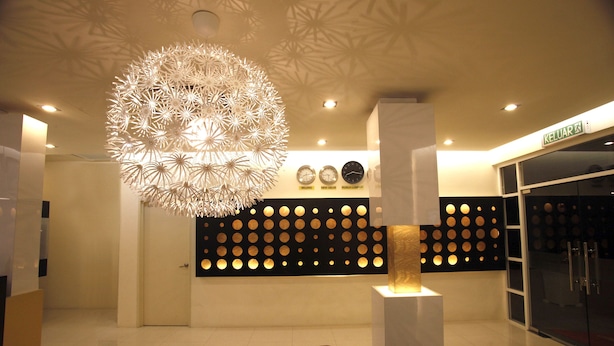 A modern lobby with a unique spherical chandelier, a reception desk, and a wall with circular patterns. - DWJ Hotel (Ipoh)
