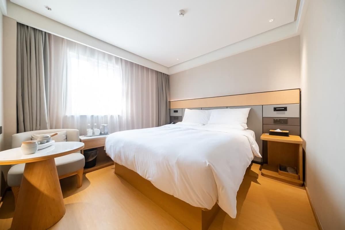 A hotel room with a large bed, bedside tables, a round table, and a sofa.