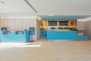A modern reception area with a blue counter, digital display, and a Costa Coffee sign. - HanTing Hotel (Beijing New China International Exhibition Center) (Beijing)
