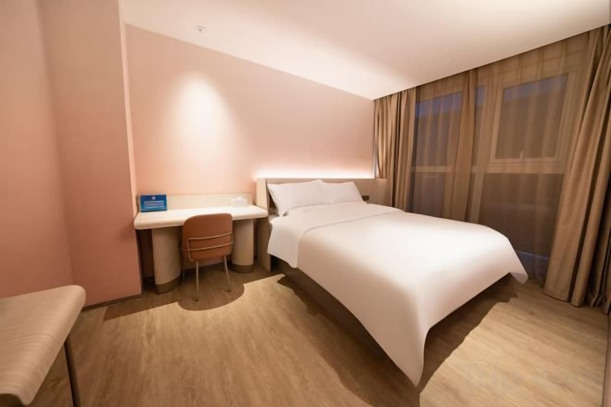 A hotel room with a bed, a desk, and a chair.