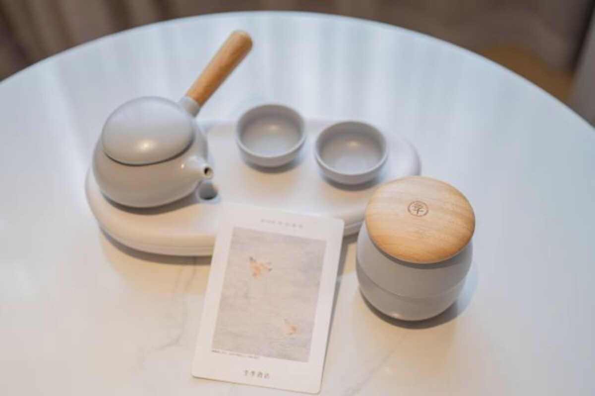 A white table with a tea set, including a teapot, cups, and a wooden container.