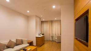 A modern hotel room with a sofa, coffee table, and a TV mounted on the wall. - Ji Hotel (Hangzhou)