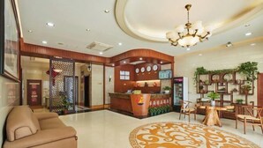 A hotel lobby with a reception desk, a sofa, a round coffee table, and a decorative rug. - Zhuoshang Boutique Hotel (Hangzhou)