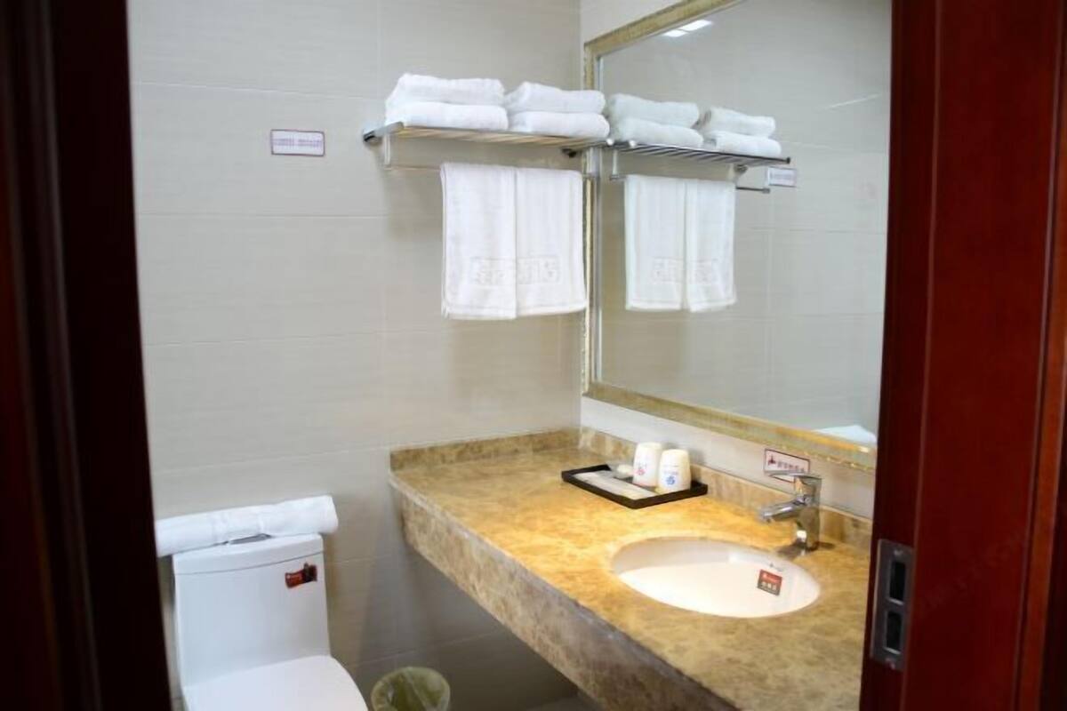 A bathroom with a sink, mirror, towel rack, and toilet.