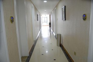 A long, narrow hotel corridor with doors on both sides, a trash bin, and a door at the end. - Zhuoshang Boutique Hotel (Hangzhou)