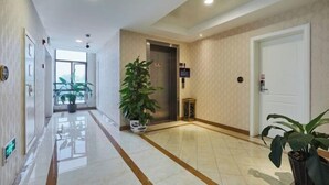 A hotel lobby with a polished floor, a reception desk, a potted plant, and an elevator. - Zhuoshang Boutique Hotel (Hangzhou)