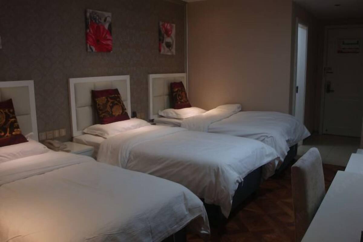 A hotel room with three beds, a desk, and a door.