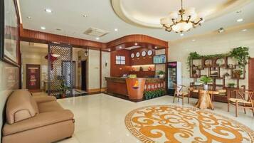 A hotel lobby with a reception desk, seating area, and decorative elements.