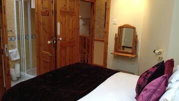 Une chambre à coucher avec un lit, une armoire en bois et une salle de bain avec douche.