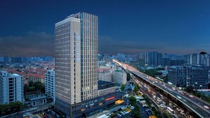 A high-rise building with a modern design, surrounded by a busy urban environment with multiple lanes of traffic and other buildings. - Gowin Hotel Hangzhou (Hangzhou)