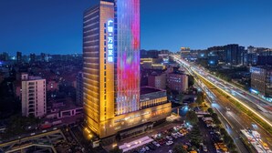 A high-rise hotel with a vertical light display and a busy highway in the background. - Gowin Hotel Hangzhou (Hangzhou)