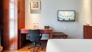 A hotel room with a wooden desk, a black office chair, a bed, a flat-screen TV mounted on the wall, and a framed picture above the desk. - Gowin Hotel Hangzhou (Hangzhou)