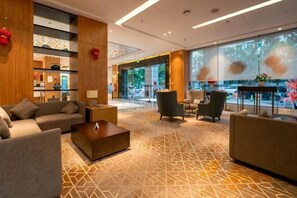 A hotel lobby with a reception desk, seating area, and large windows. - Yunnan Weiju Golden Eagle Grand Hotel (Kunming Railway Station Shuangqiao Night Market Style Street) (Kunming)