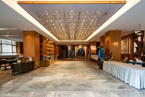 A spacious lobby with a high ceiling, a reception desk, and a seating area. - Yunnan Weiju Golden Eagle Grand Hotel (Kunming Railway Station Shuangqiao Night Market Style Street) (Kunming)