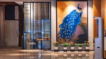 A hotel lobby with a peacock mural, a seating area, and a reception desk.