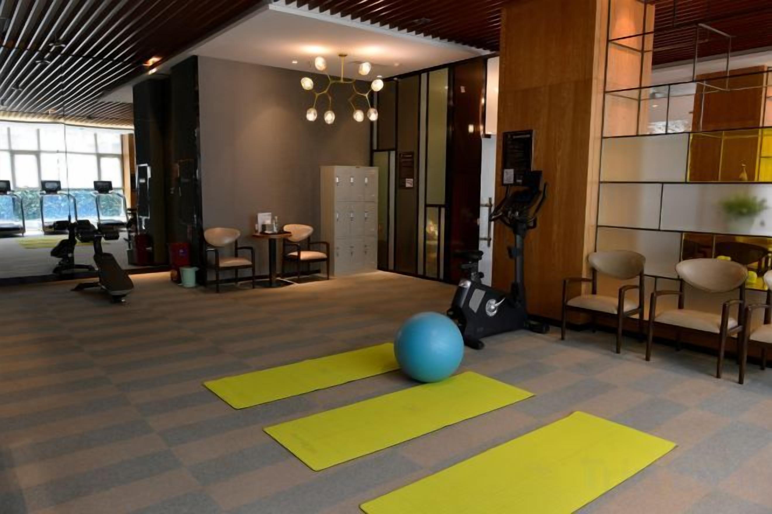 Et fitnessrum med træningsudstyr, yogamåtter og en stor træningsbold.