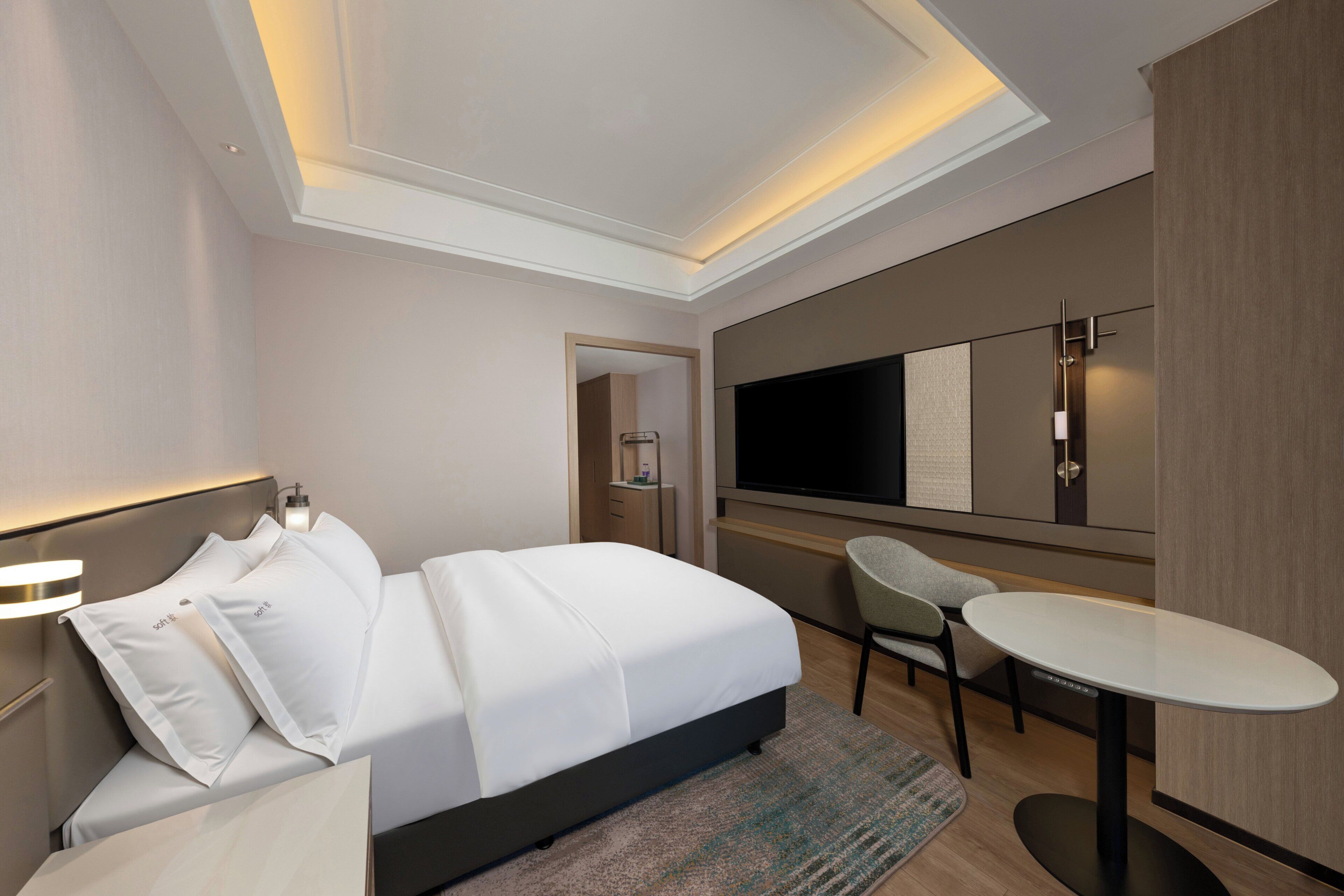 Una camera d'albergo moderna con un letto grande, una scrivania, una sedia, una TV a schermo piatto e un armadio.