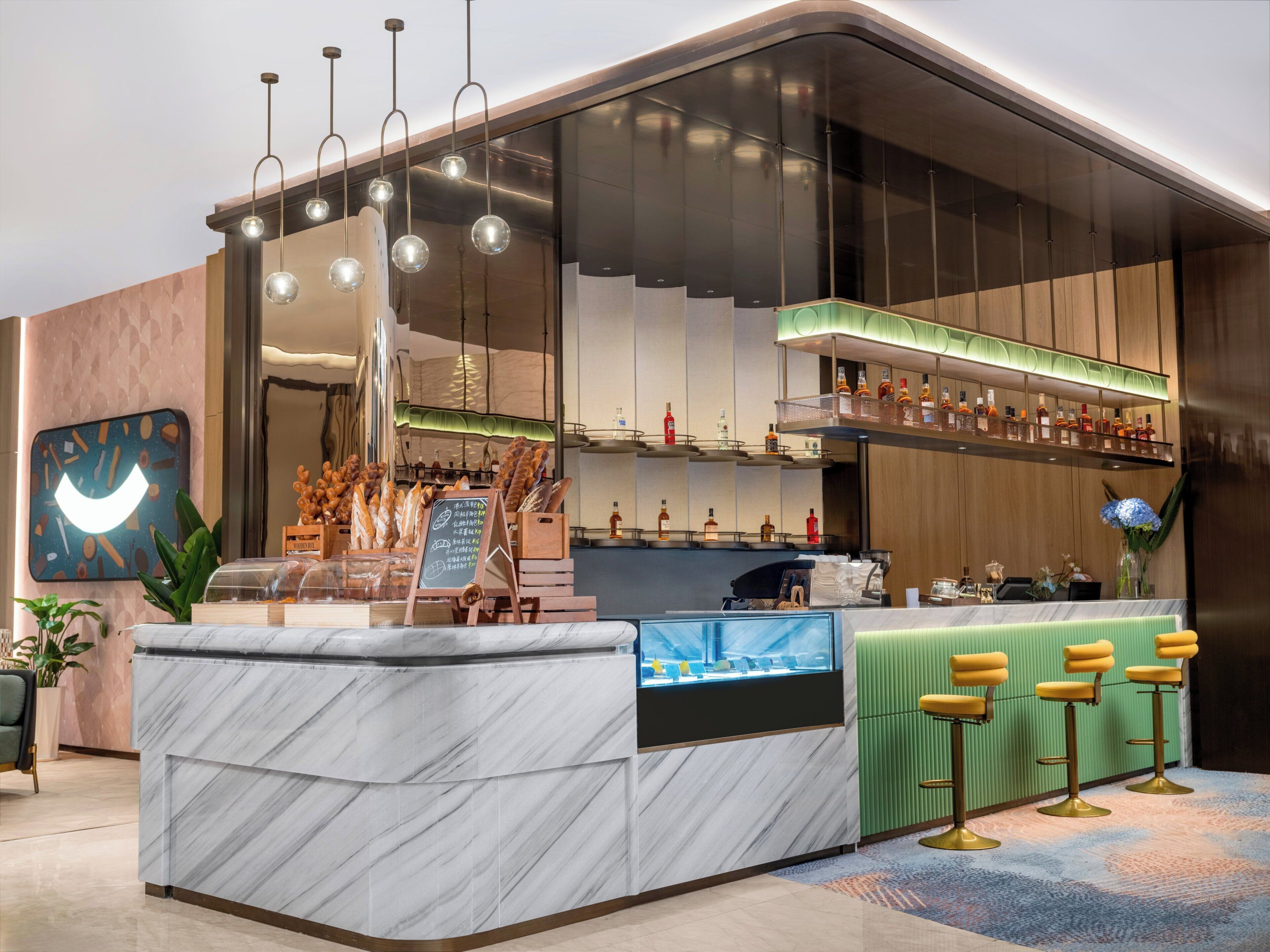 A modern bar area with a marble countertop, hanging spherical lights, and a variety of bottles on shelves.