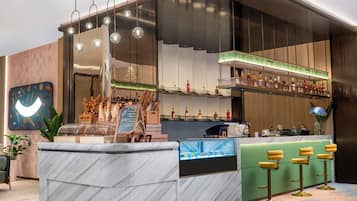 A modern bar area with a marble countertop, hanging spherical lights, and a variety of bottles on shelves.