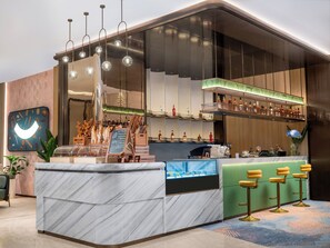Zona de bar moderna con encimera de mármol, luces esféricas colgantes y una selección de botellas en estanterías.