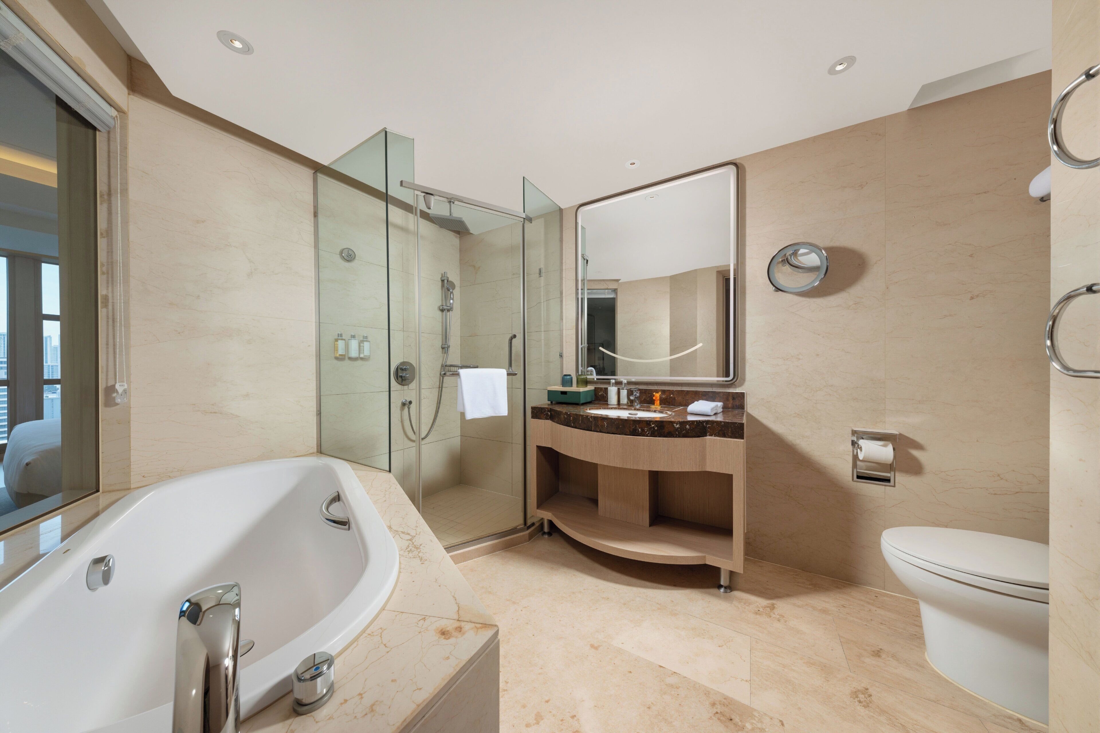 Et moderne badeværelse med en glasafskærmet brusekabine, et fritstående badekar, et toiletbord med et spejl og et toilet.