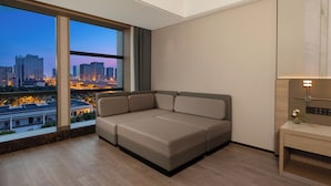 Quarto moderno com uma janela grande, um sofá, uma mesa de cabeceira e um criado-mudo.