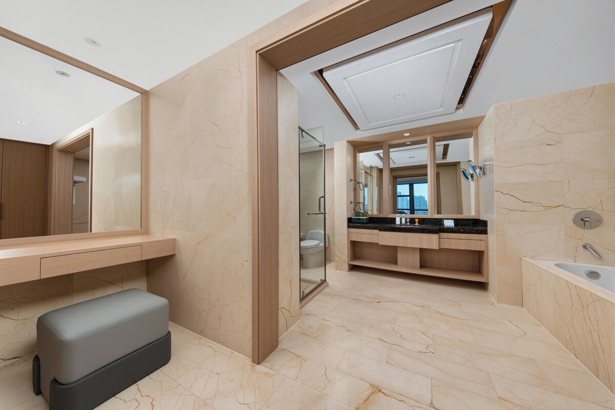Un baño moderno con un espejo grande, un banco, una bañera y un tocador con lavabo.
