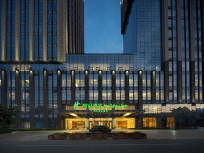 Un hotel moderno con un ingresso importante, ampie finestre e una facciata ben illuminata.