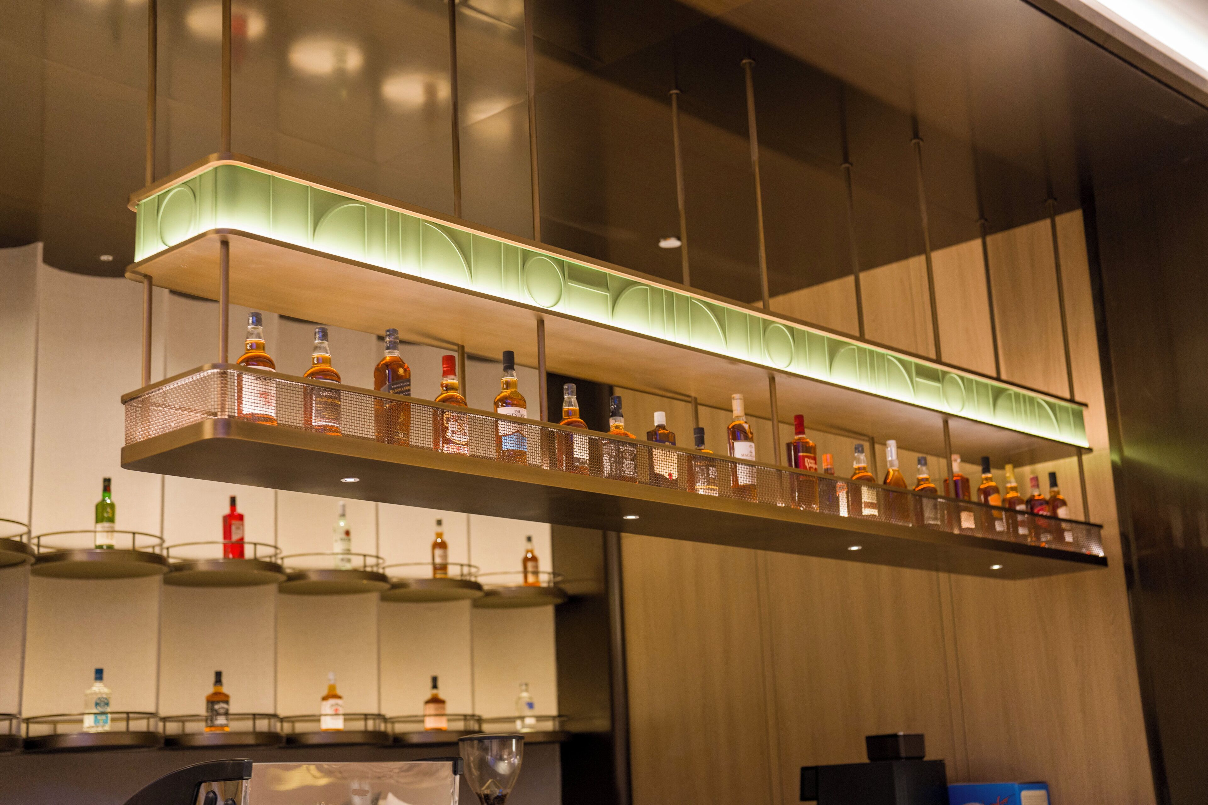 Uma área de bar com várias prateleiras de garrafas, um lustre e um balcão.