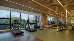 Uma academia com esteiras, bolas de exercício e um grande espelho.