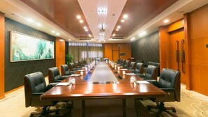A conference room with a long table, multiple chairs, and a large painting on the wall.