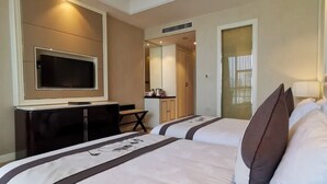 A hotel room with two beds, a TV mounted on the wall, a desk, and a mirror.
