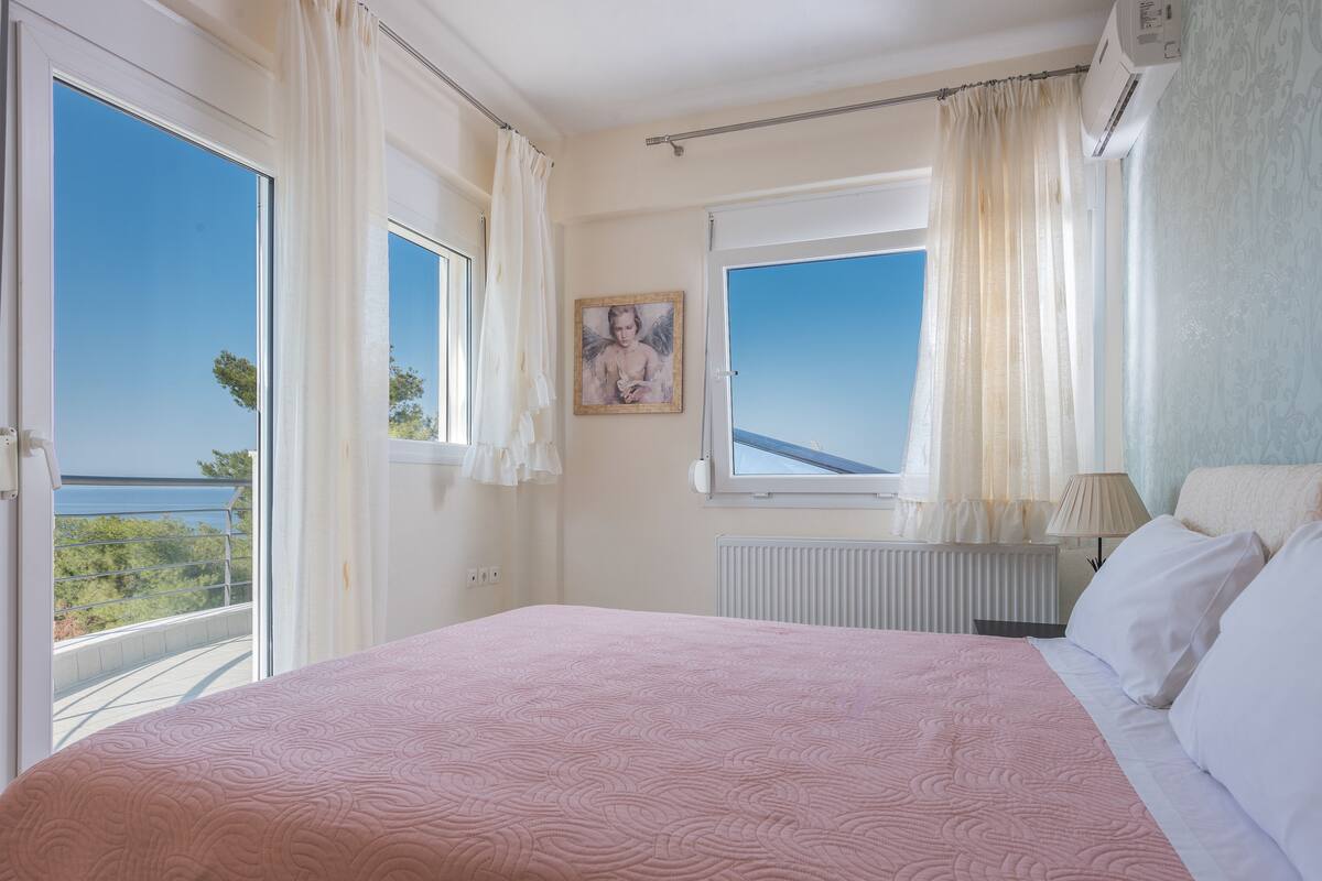 Une chambre avec un grand lit, une fenêtre avec des rideaux, un radiateur et un tableau au mur.