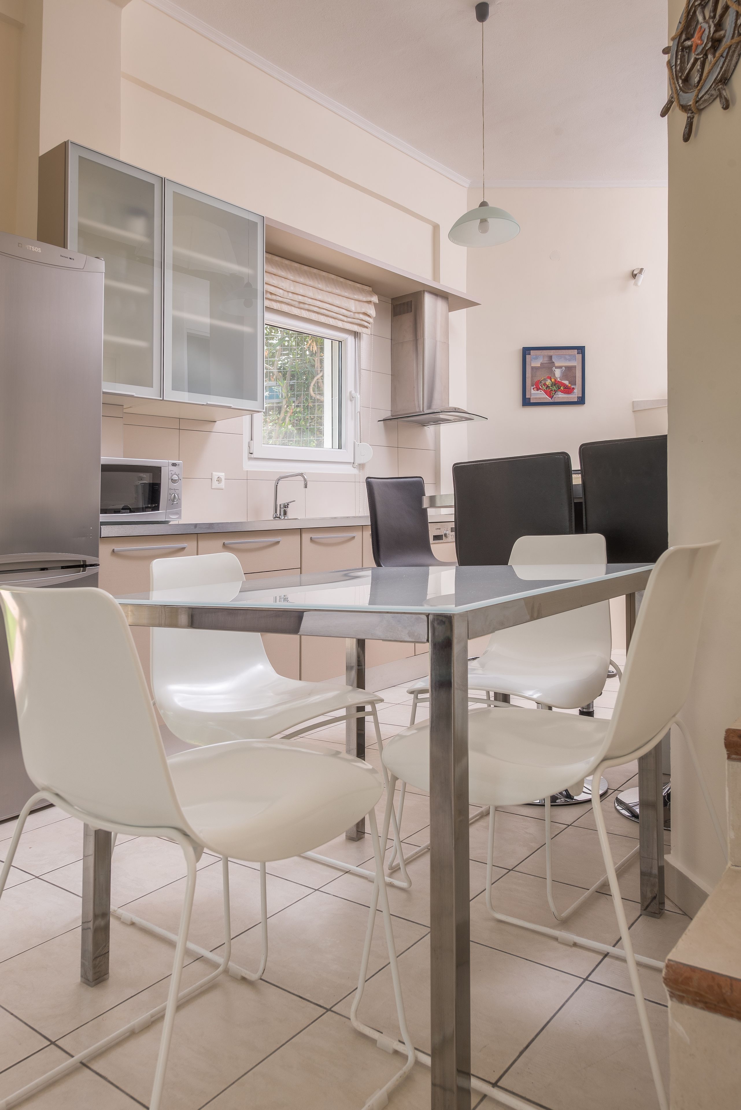 A modern kitchen with a dining table, chairs, a refrigerator, a microwave, and cabinets.