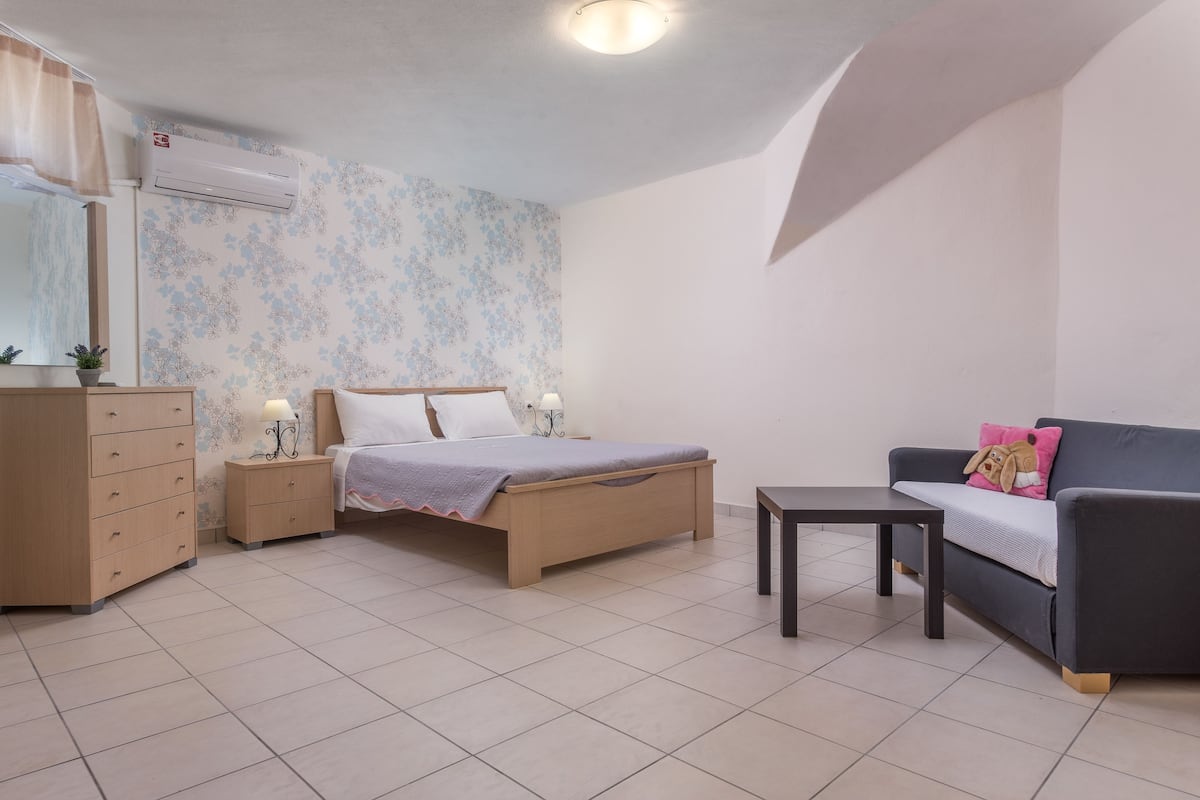 Une chambre à coucher comprenant un lit, une commode, une table de chevet, une table et un canapé.